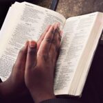Praying hands on the Bible